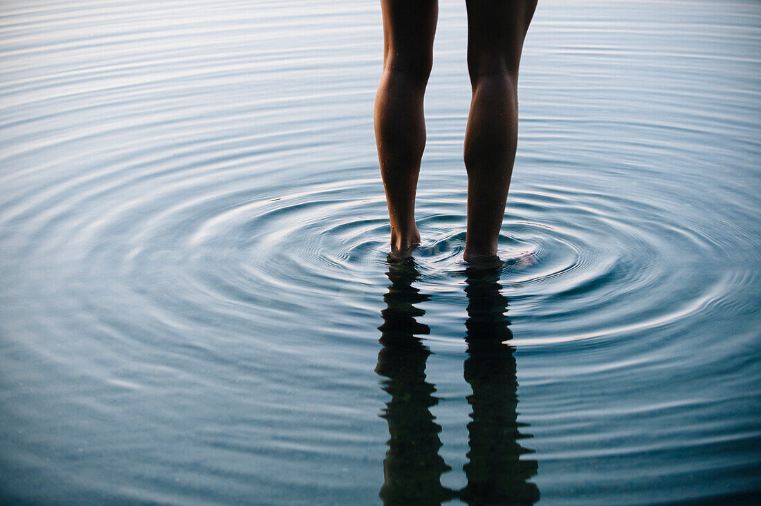 Reflection of legs of Korean woman with ripples in water, Bremerton, wa, USA