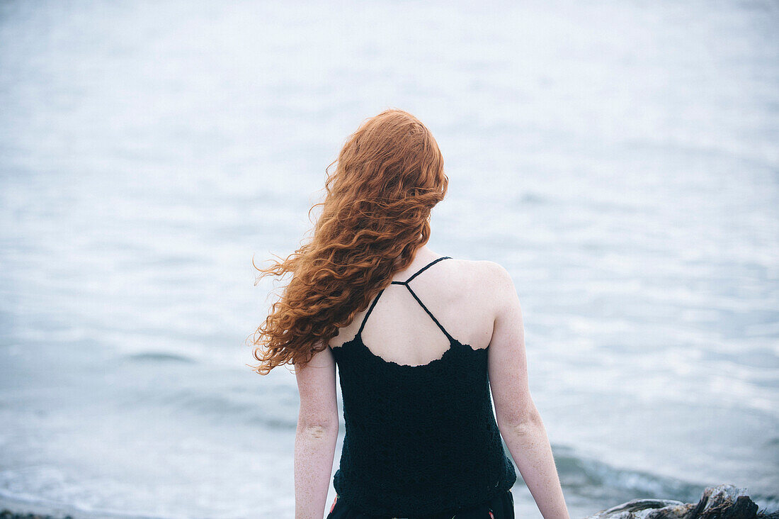 Rear view of girl sitting on beach, Bainbridge Island, WA, USA