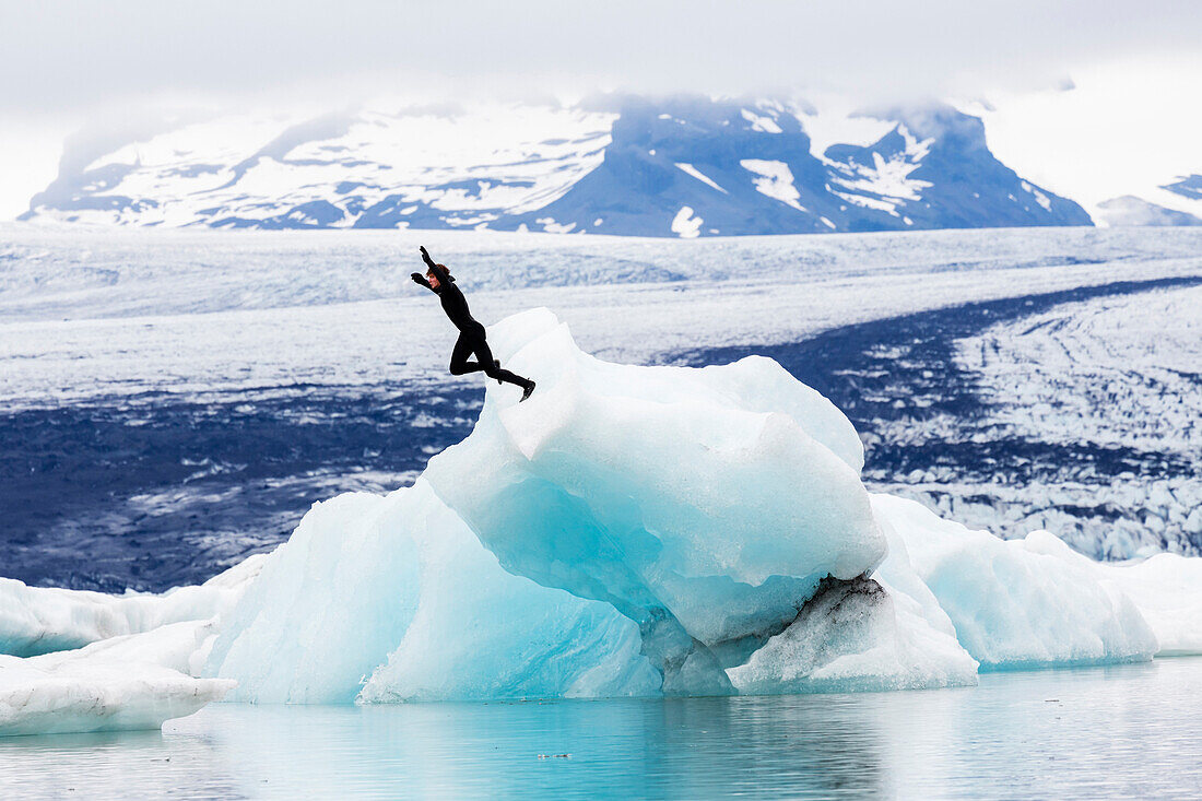 Caucasian surfer jumping into glacial water, Jokulsarlon, Iceland, Iceland