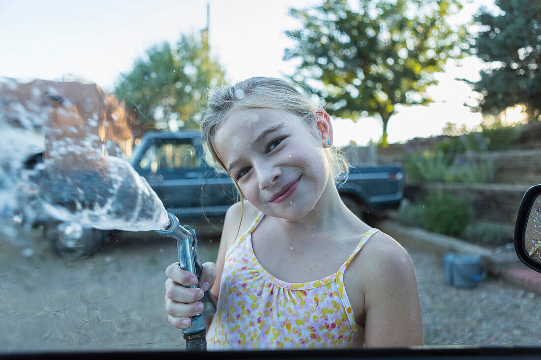 Caucasian girl spraying water from hose outdoors, Santa Fe, NewMexico, USA