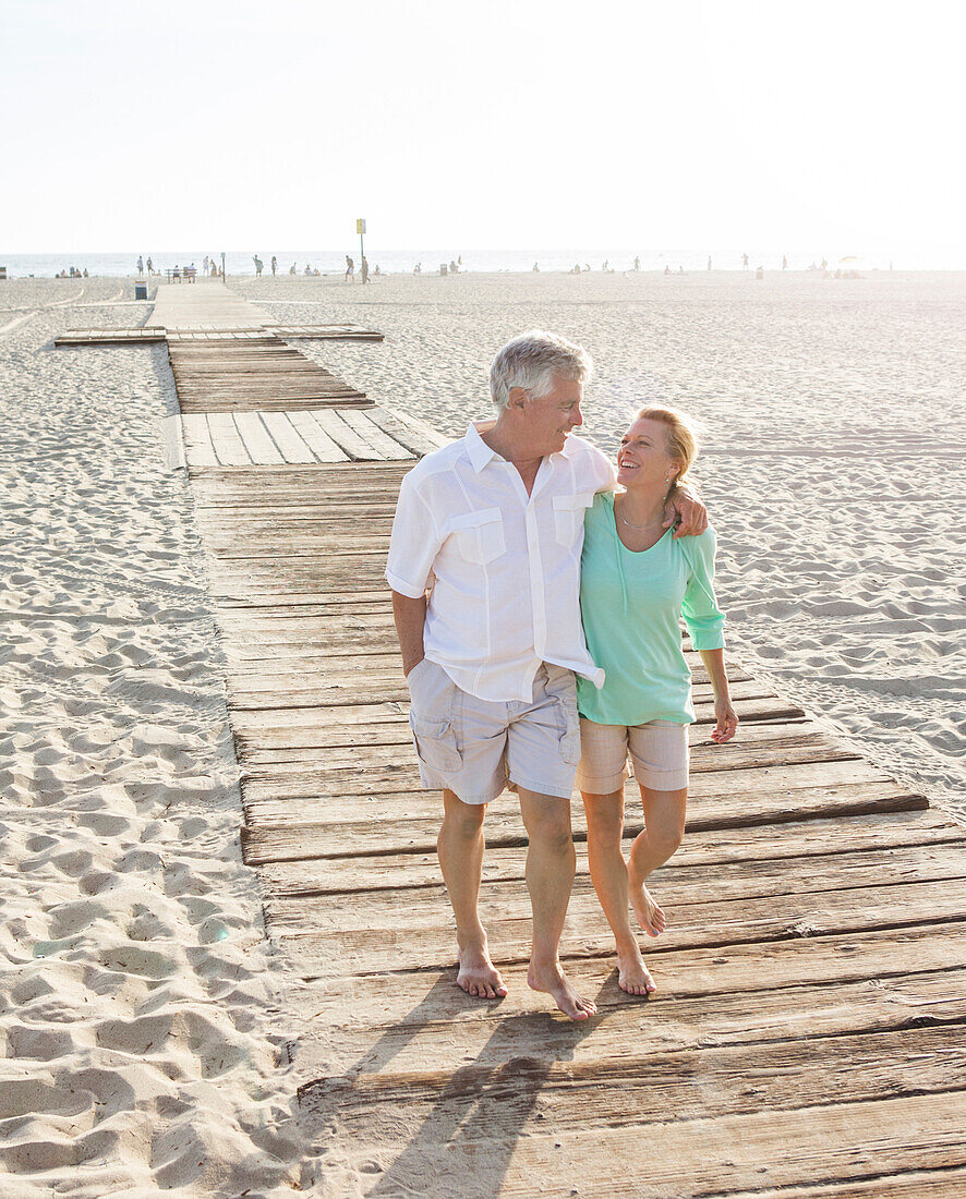 Caucasian couple walking on wooden boardwalk on beach, Santa Monica, California, USA
