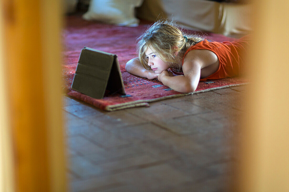 Caucasian girl watching digital tablet on floor, Santa Fe, NewMexico, USA