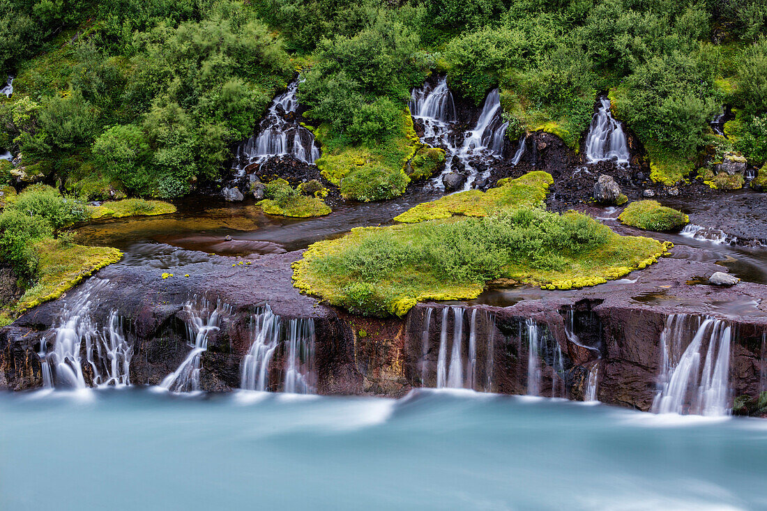 Waterfall flowing over rock formations to lake, Borgarnes, Iceland, Iceland