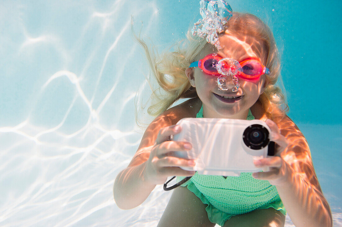 Caucasian girl taking photograph underwater in pool, Huntington Station, New York, USA