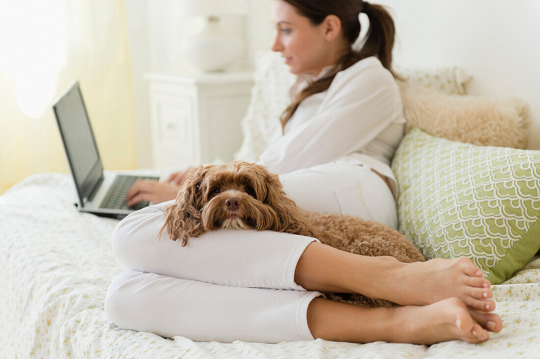 Caucasian woman using laptop with pet dog, Jersey City, New Jersey, USA