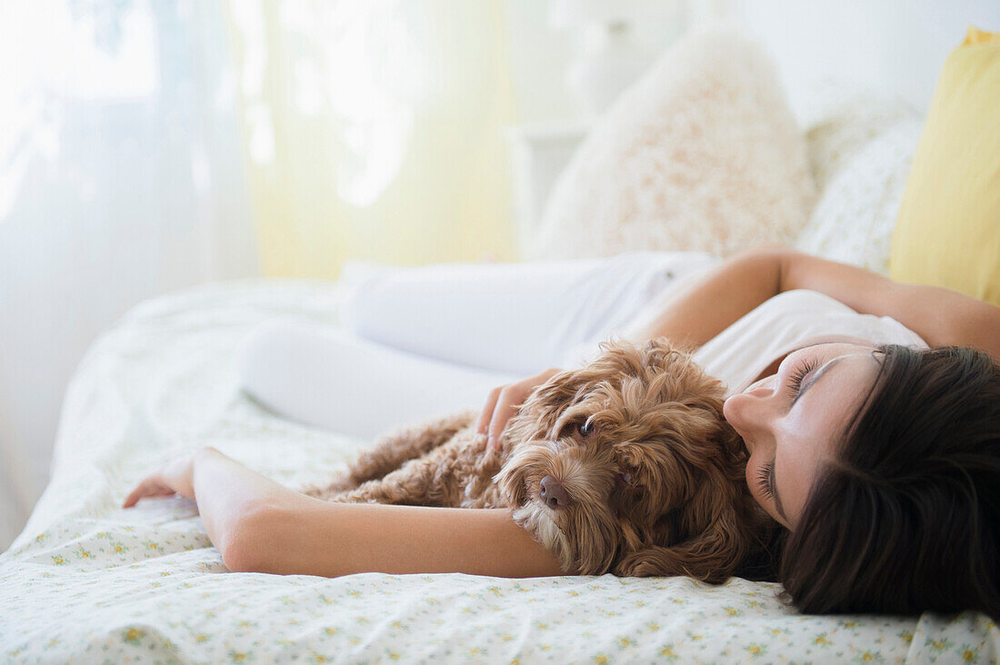 Caucasian woman hugging pet dog in bed, Jersey City, New Jersey, USA