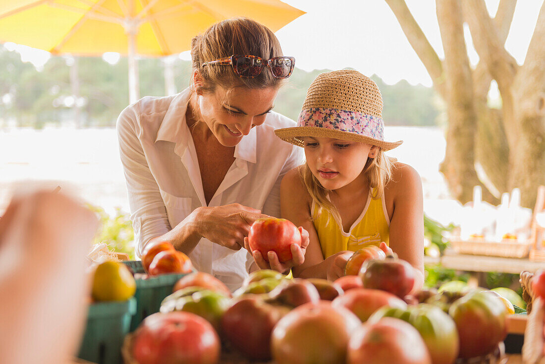 Mixed race mother and daughter browsing produce at farmers market, Virginia Beach, VA, USA