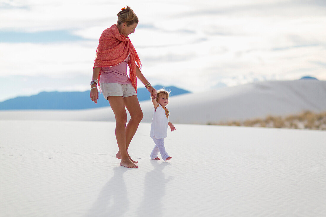 Caucasian mother and son walking on sand dune, White Sands, New Mexico, USA
