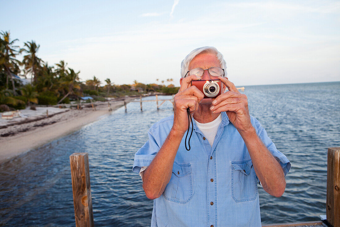 Caucasian man taking photographs on beach, Florida Keys, Florida, USA