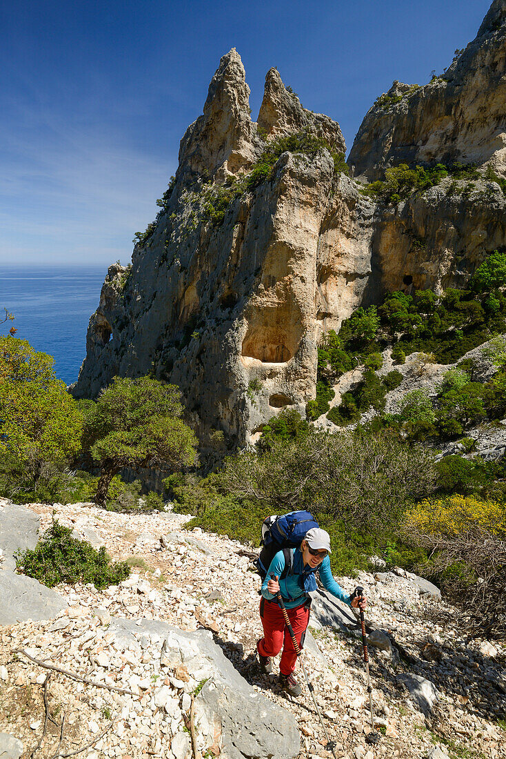 Eine junge Frau mit Trekkingausrüstung wandert oberhalb des Meeres entlang der gebirgigen Küste, Golfo di Orosei, Selvaggio Blu, Sardinien, Italien, Europa