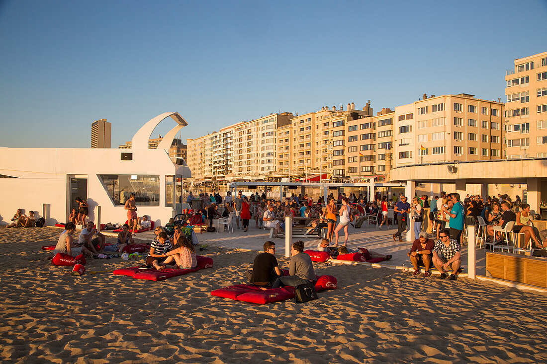 People chilling on the beach at a beach lounge with apartment buildings behind, Ostend, Flanders, Flemish Region, Belgium