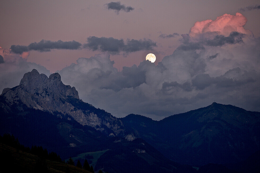 Full moon between clouds in the evening sky in the mountains, Rote Flueh, Gimpel, Hochwiesler, Tannheimer Tal, Tyrol, Austria