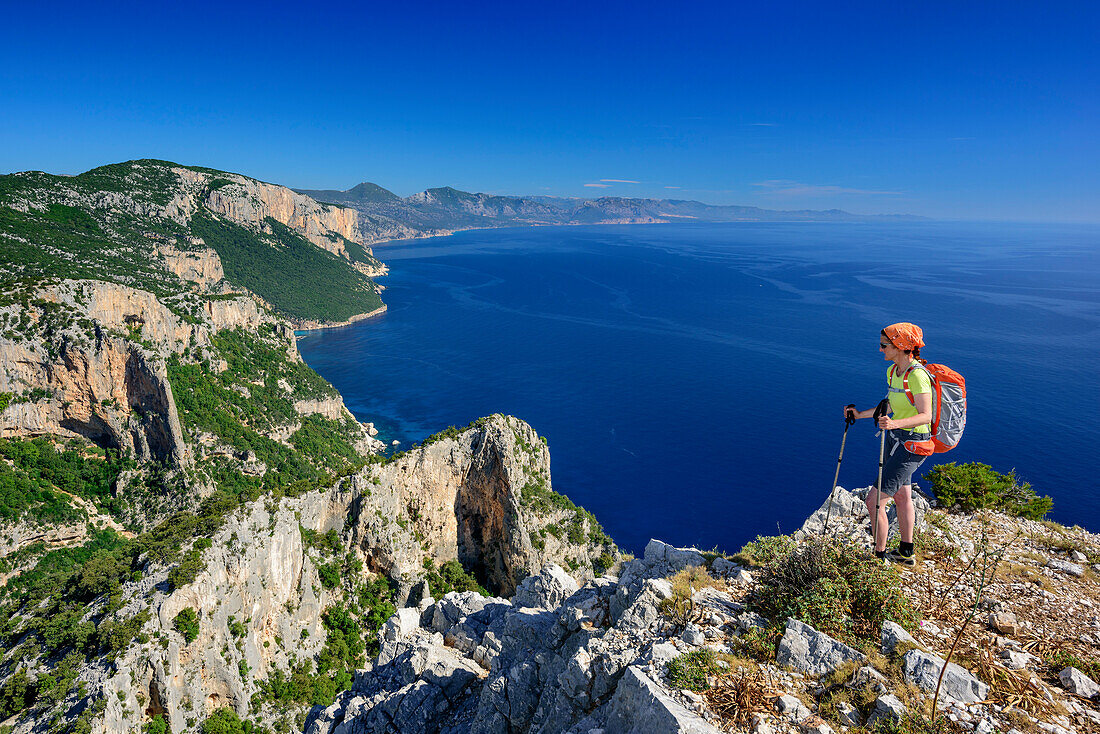 Frau wandert am Selvaggio Blu über Felsgrat mit Blick auf Mittelmeer, Selvaggio Blu, Nationalpark Golfo di Orosei e del Gennargentu, Sardinien, Italien