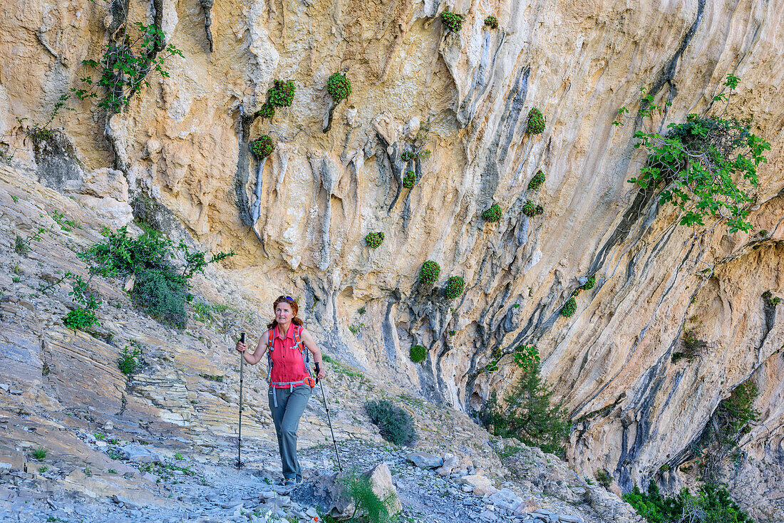 Woman hiking Selvaggio Blu crossing rock face with tufa, Selvaggio Blu, National Park of the Bay of Orosei and Gennargentu, Sardinia, Italy