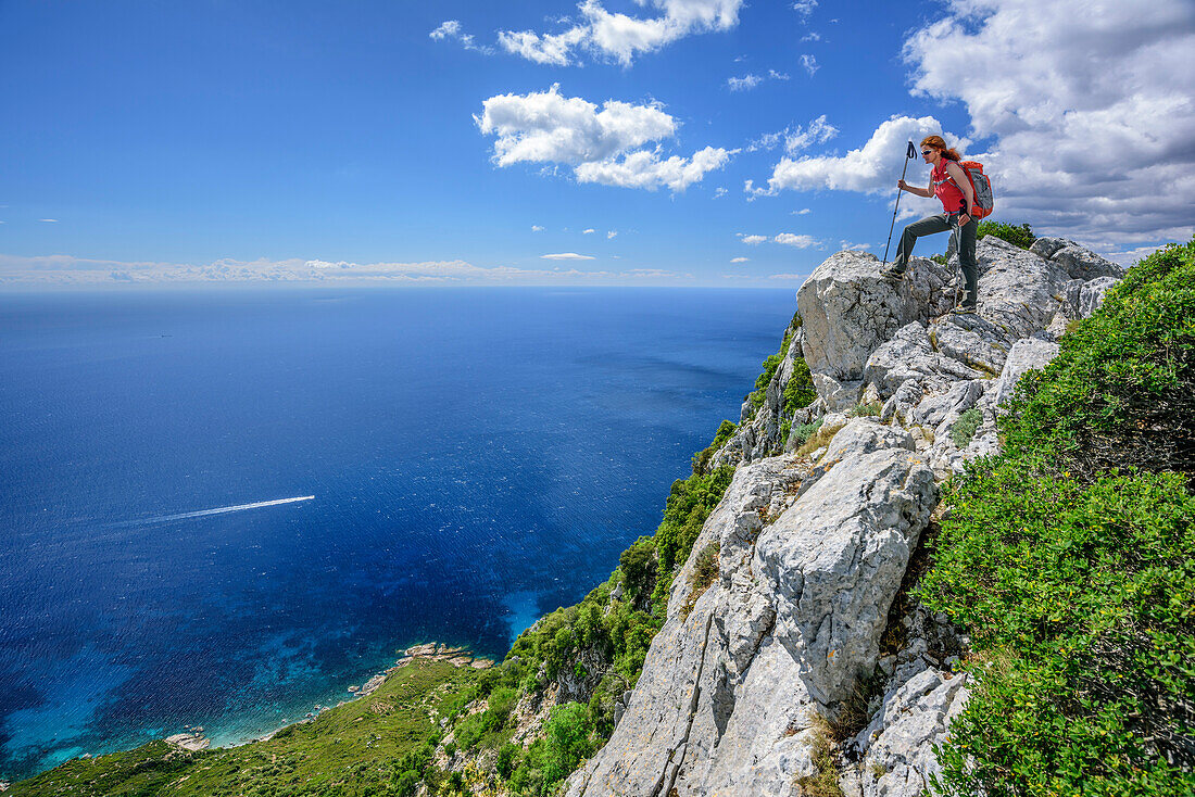 Woman hiking Selvaggio Blu standing at cliff and looking at coast of Golfo di Orosei, Selvaggio Blu, National Park of the Bay of Orosei and Gennargentu, Sardinia, Italy