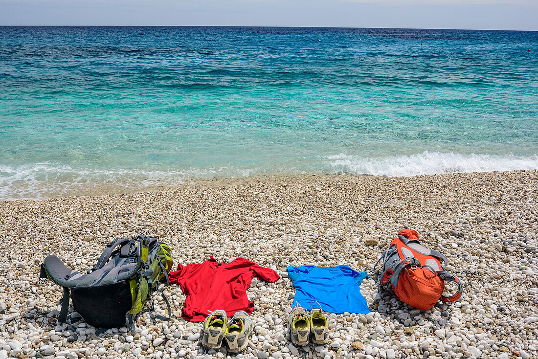 Rucksäcke und Kleidung liegen am Strand Cala Sisine am Mittelmeer, Cala Sisine, Selvaggio Blu, Nationalpark Golfo di Orosei e del Gennargentu, Sardinien, Italien