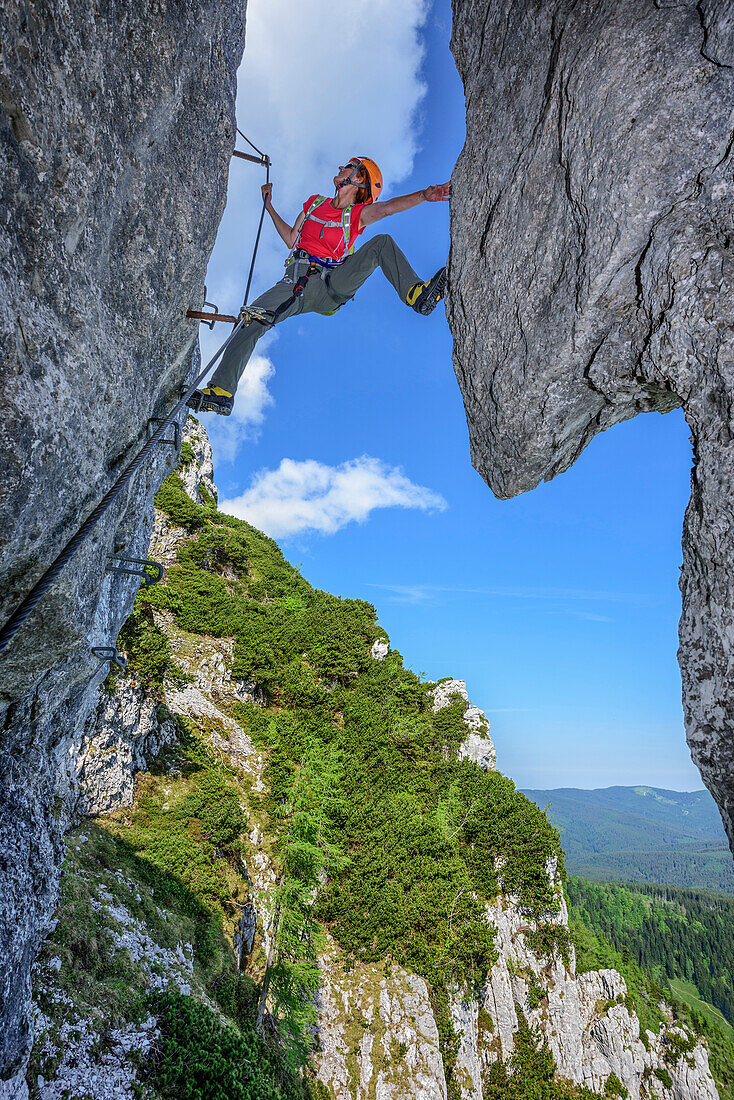Woman ascending on steep fixed rope route, fixed rope route Pidinger Klettersteig, Hochstaufen, Chiemgau Alps, Chiemgau, Upper Bavaria, Bavaria, Germany