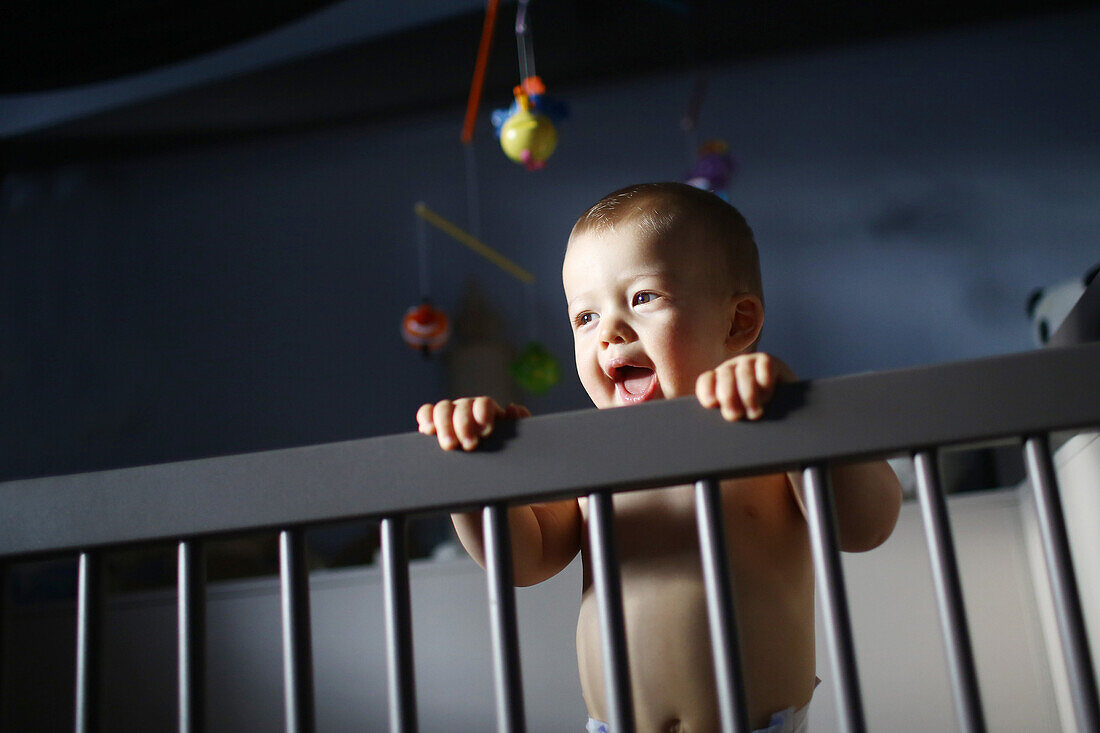 A baby boy standing in his bed