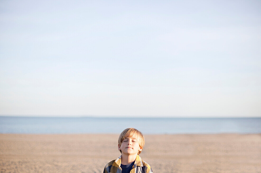 Portrait of a young boy with eyes closed at the beach