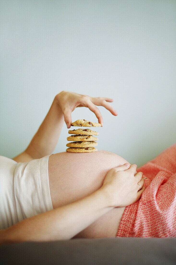 Kekse auf dem Bauch einer im 7. Monat schwangeren Frau