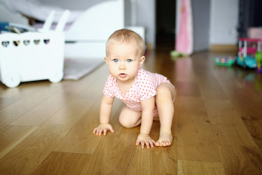 A baby girl walking with 4 legs in her room