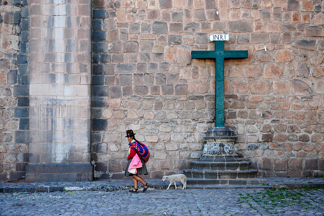 Woman xearing traditional clothes walking along a church in Plaza de Armas,Cuzco , Peru,South America