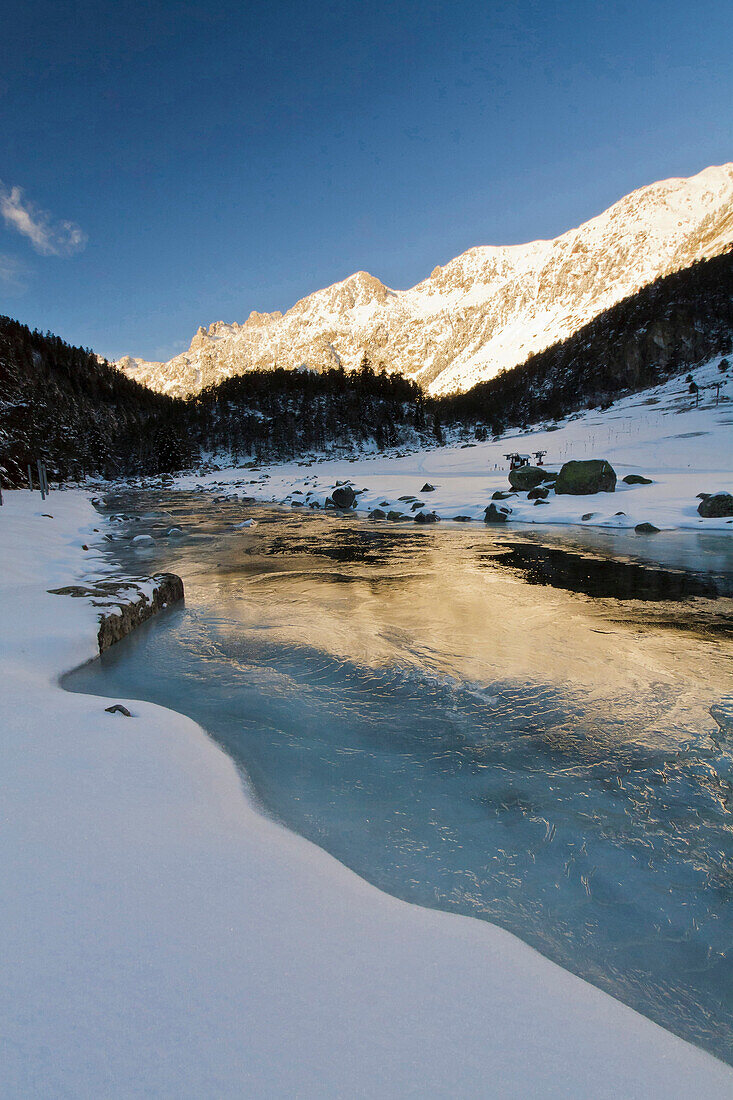 France, Midi Pyrenees, Hautes Pyrenees, First light of day on the summits of Marcadau valley reflected in the frozen river