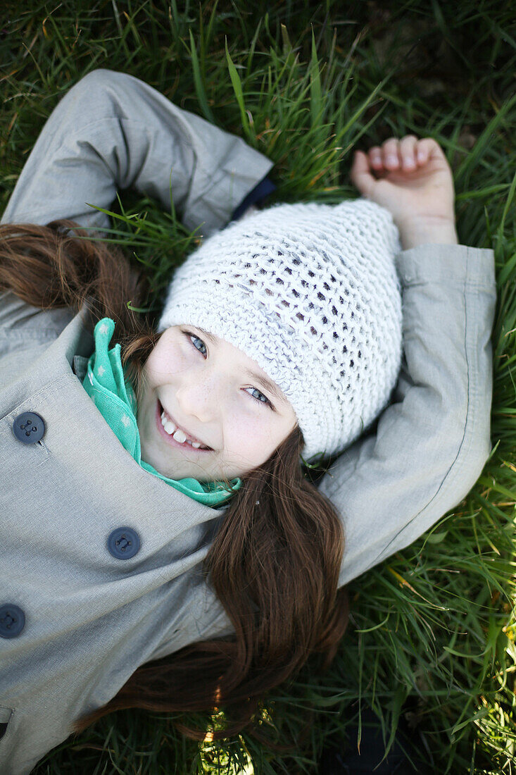Portrait of a 7 years old girl, she is lying in the grass