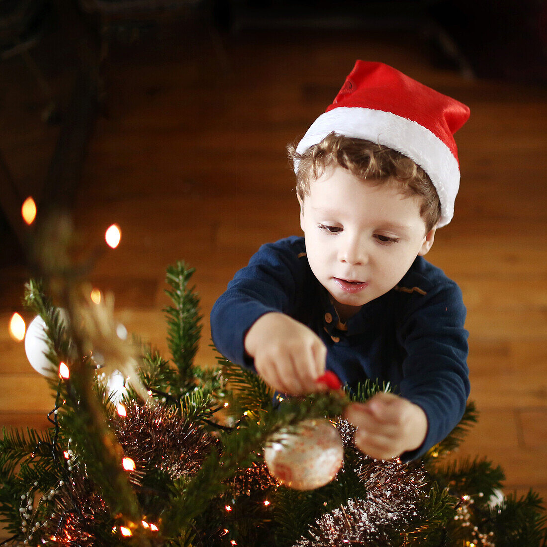 A 2 years old boy decorating a christmas tree