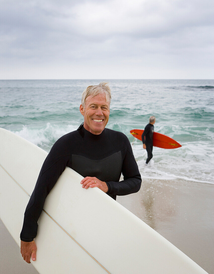 Senior man holding surfboard at beach