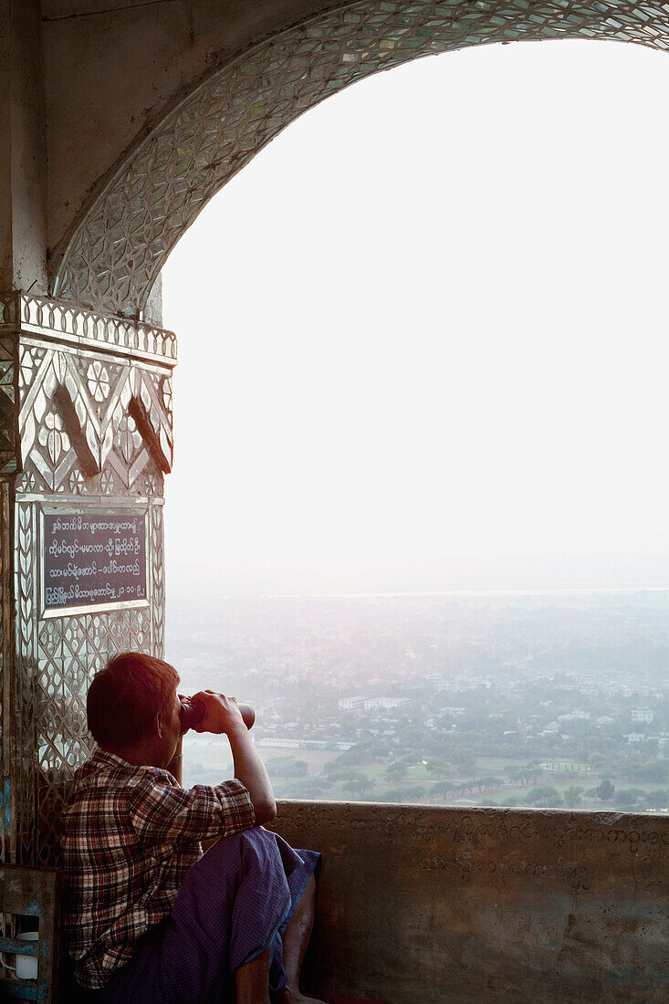 Asian man looking at view through binoculars