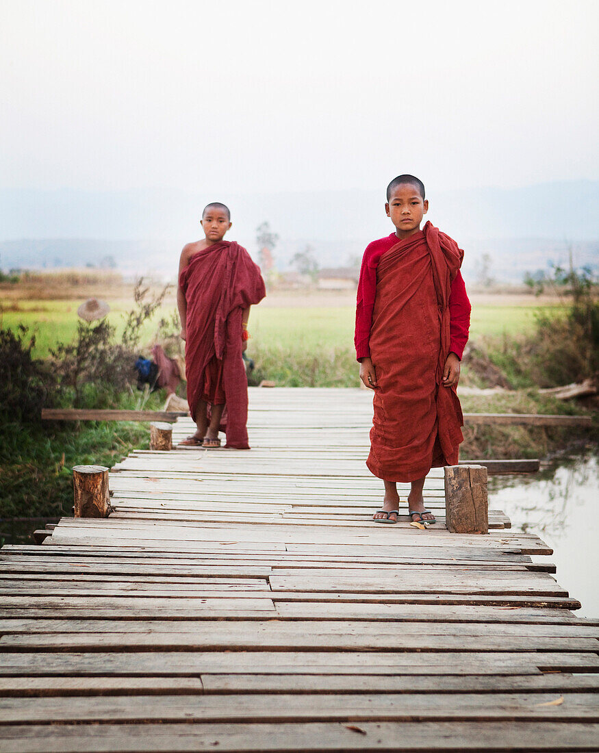 Asian boys in traditional robes walking on bridge