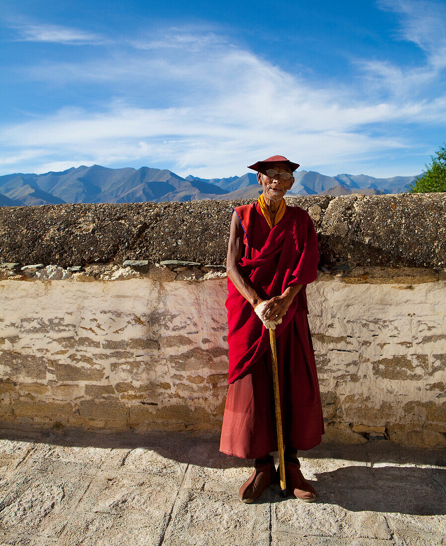 Elderly Tibetan monk with walking stick