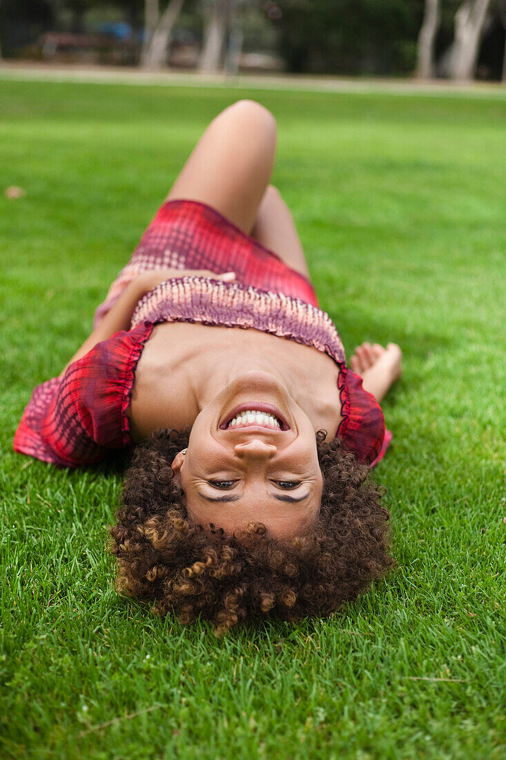 Smiling mixed race woman laying in grass
