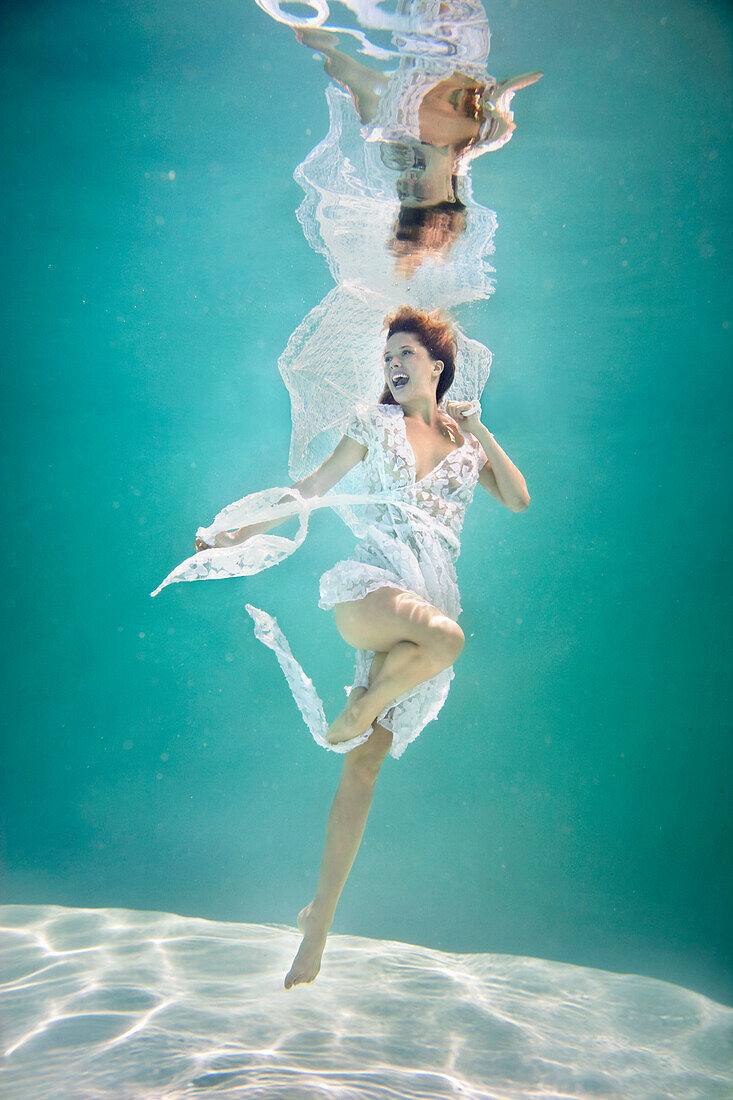 Caucasian woman in elegant dress under water