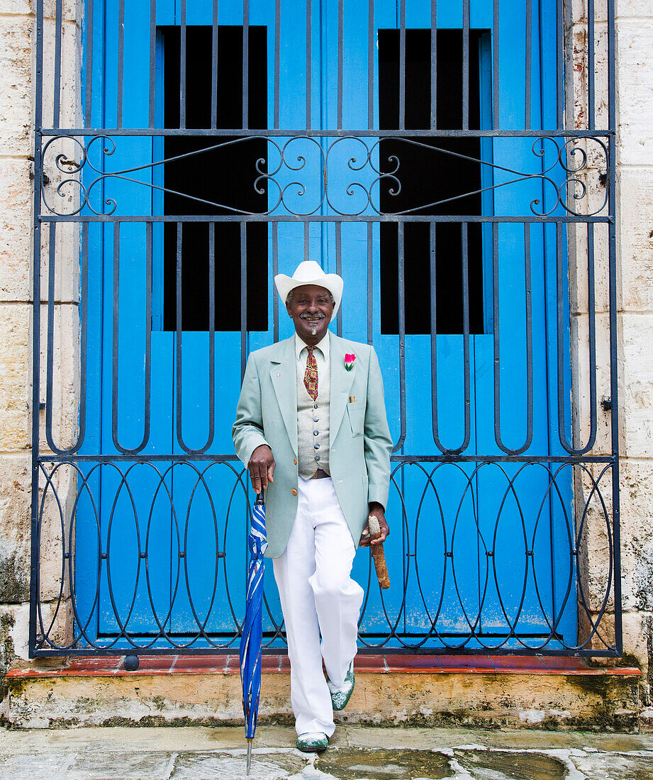 Portrait of well-dressed Black man in front of gated door