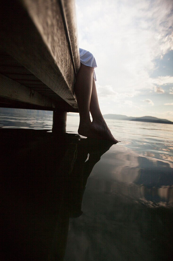 Caucasian woman dipping feet in still lake