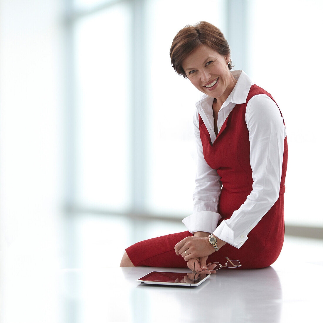 Kaukasische Geschäftsfrau, die mit einem digitalen Tablet auf einem Tisch sitzt