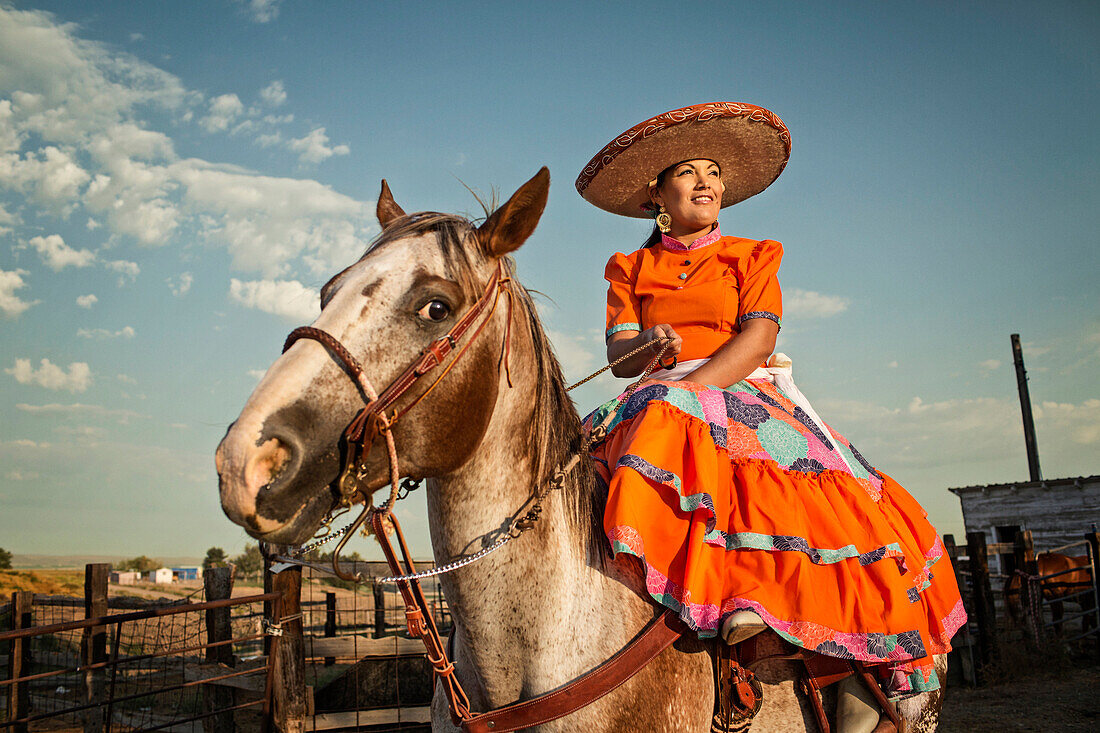 Hispanic woman in traditional dress on horse