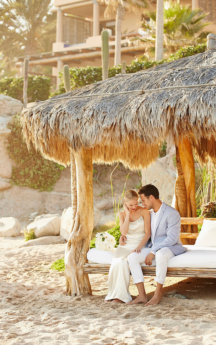 Newlywed couple relaxing in cabana