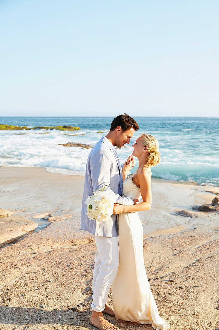 Newlywed couple hugging on beach