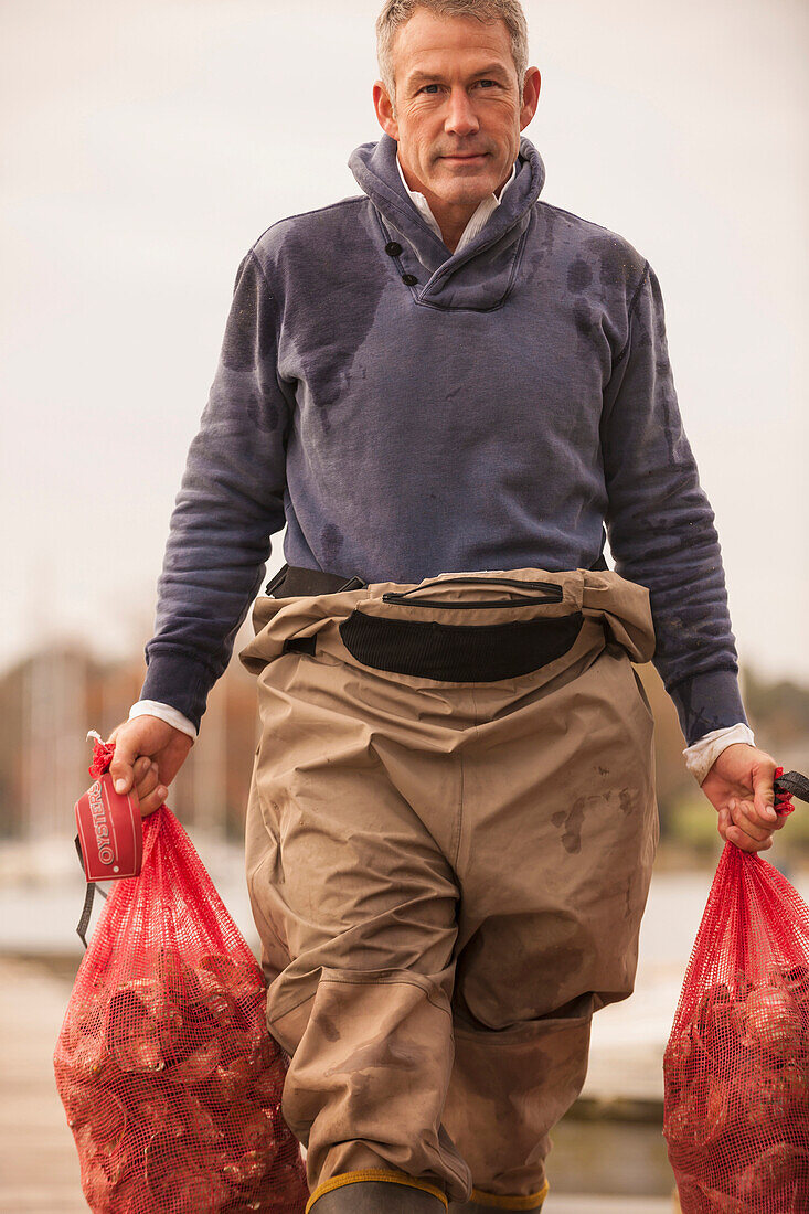 Caucasian fisherman carrying catch on dock