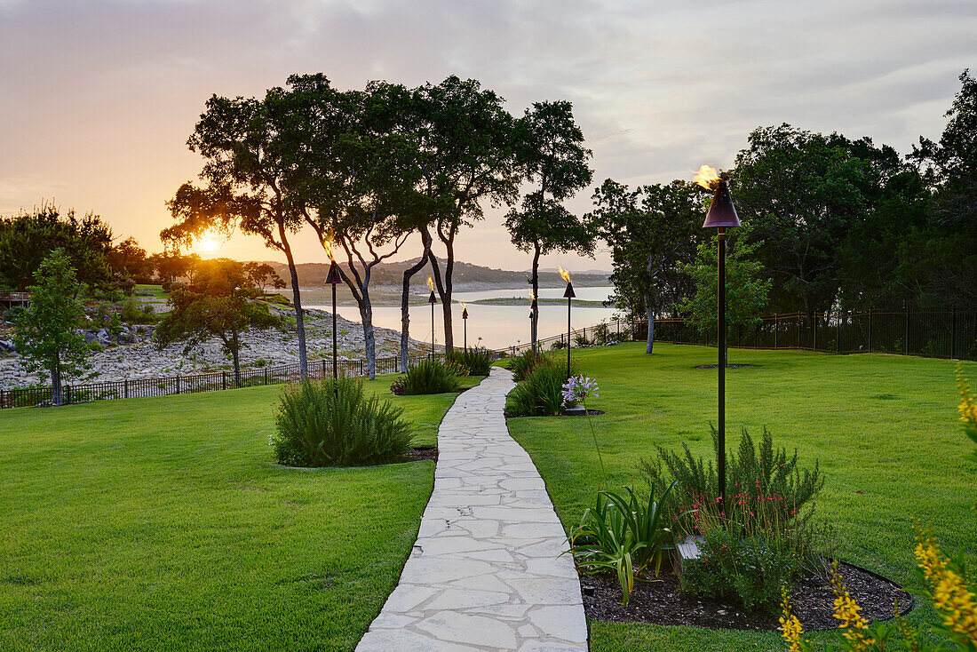 Stone Path to Water Lined with Tiki Torches at Sunset