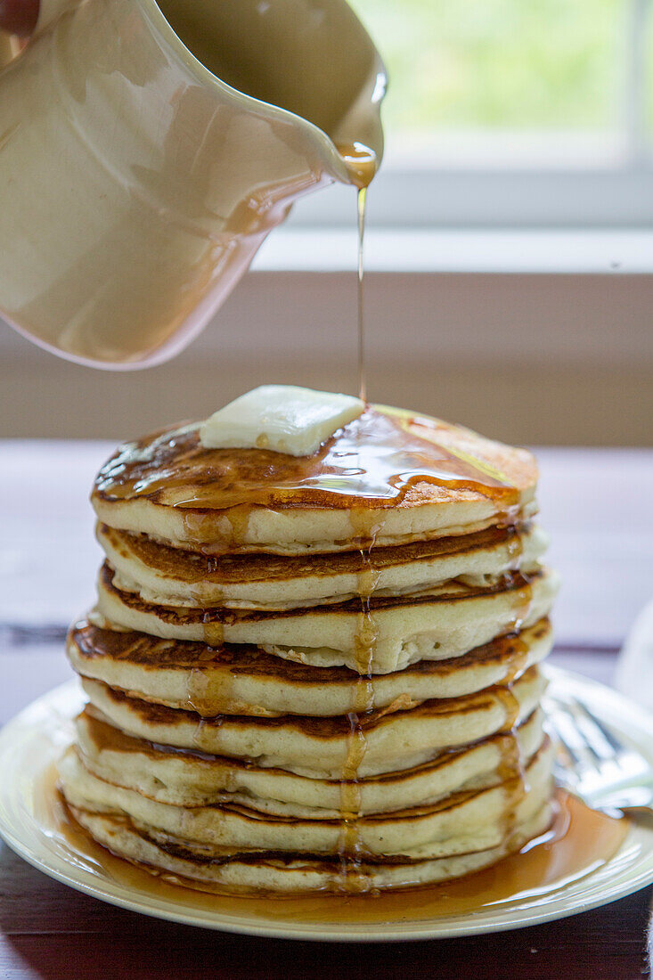Maple Syrup Being Poured Over Stack of Pancakes