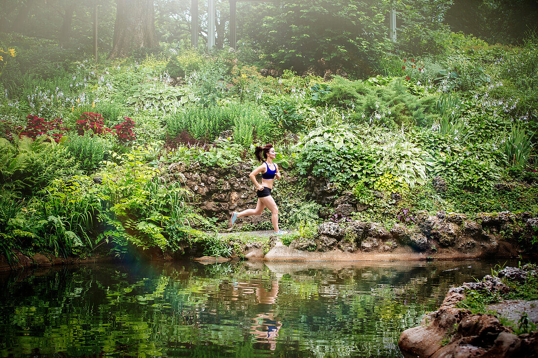 Caucasian woman running near lake in park, St Louis, MO, USA