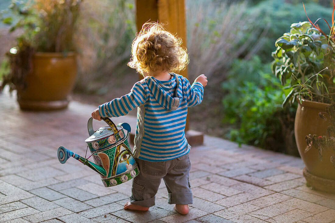 Caucasian baby carrying watering can, Santa Fe, New Mexico, USA