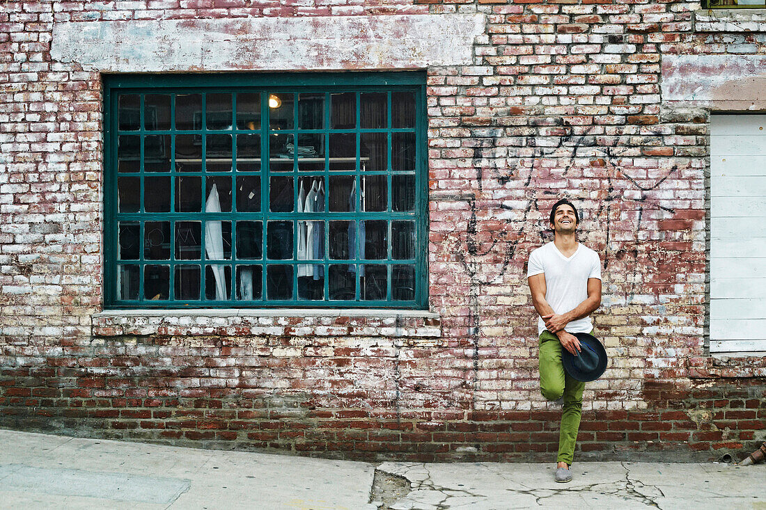 Mixed race man leaning on industrial building, Los Angeles, California, USA