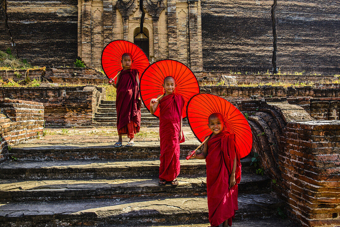 Asian monks standing under umbrellas near historic temple, Mingun, Mandala, Myanmar, Mingun, Mandalay, Myanmar