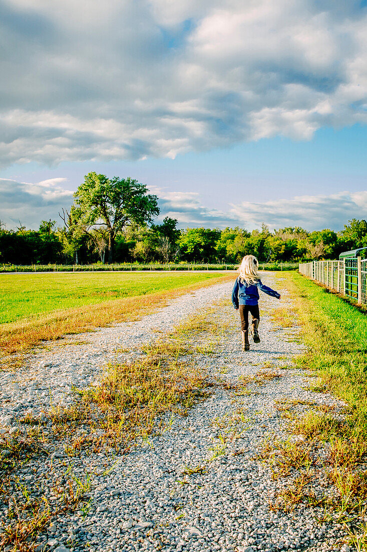 Caucasian girl walking on dirt road on ranch, C1