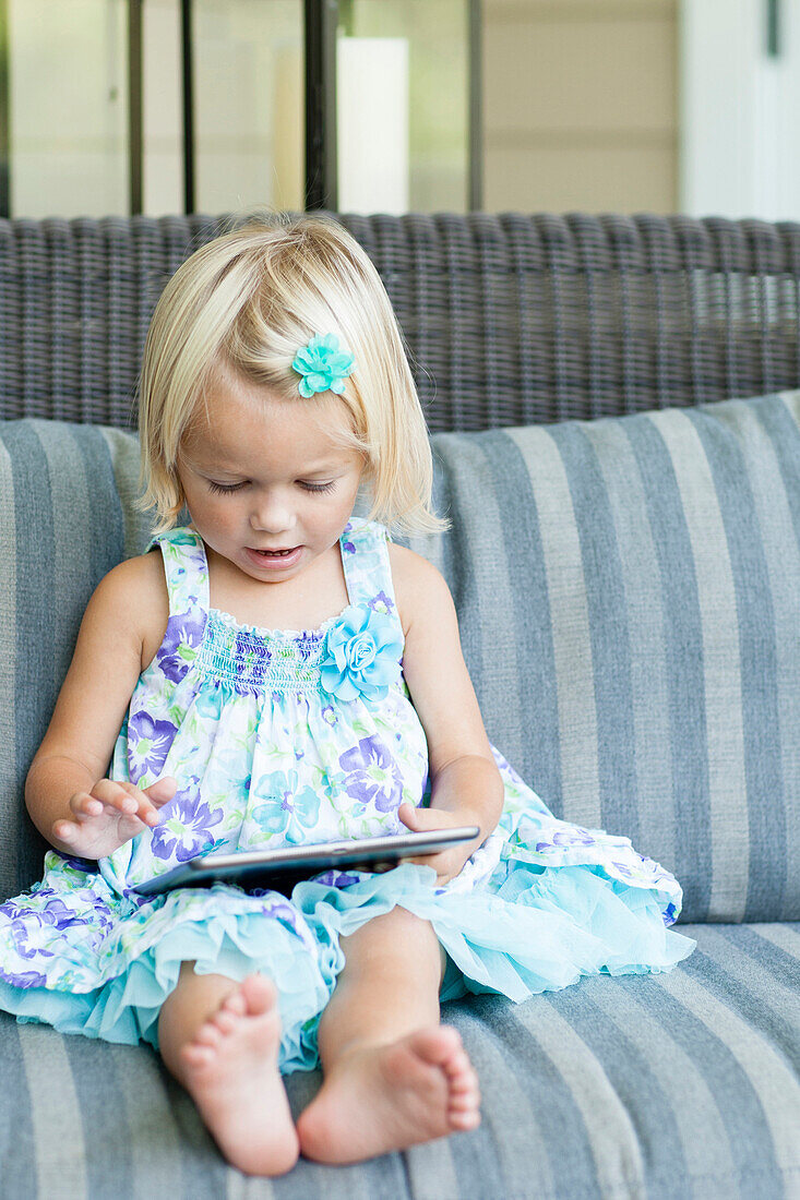 Caucasian girl using digital tablet on sofa, C1